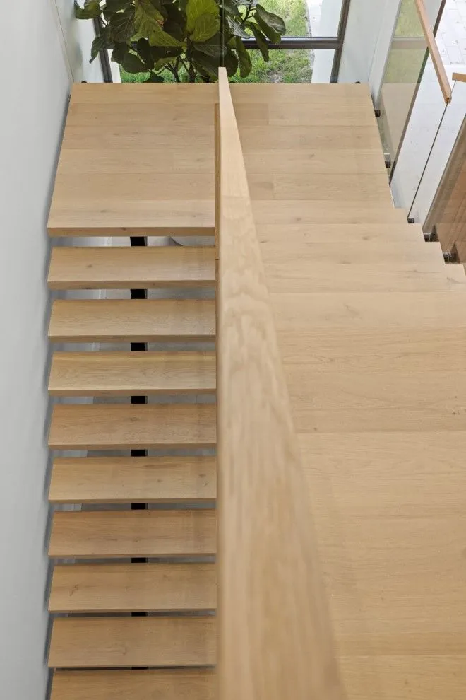 Top-down view of a modern floating staircase with light oak treads.