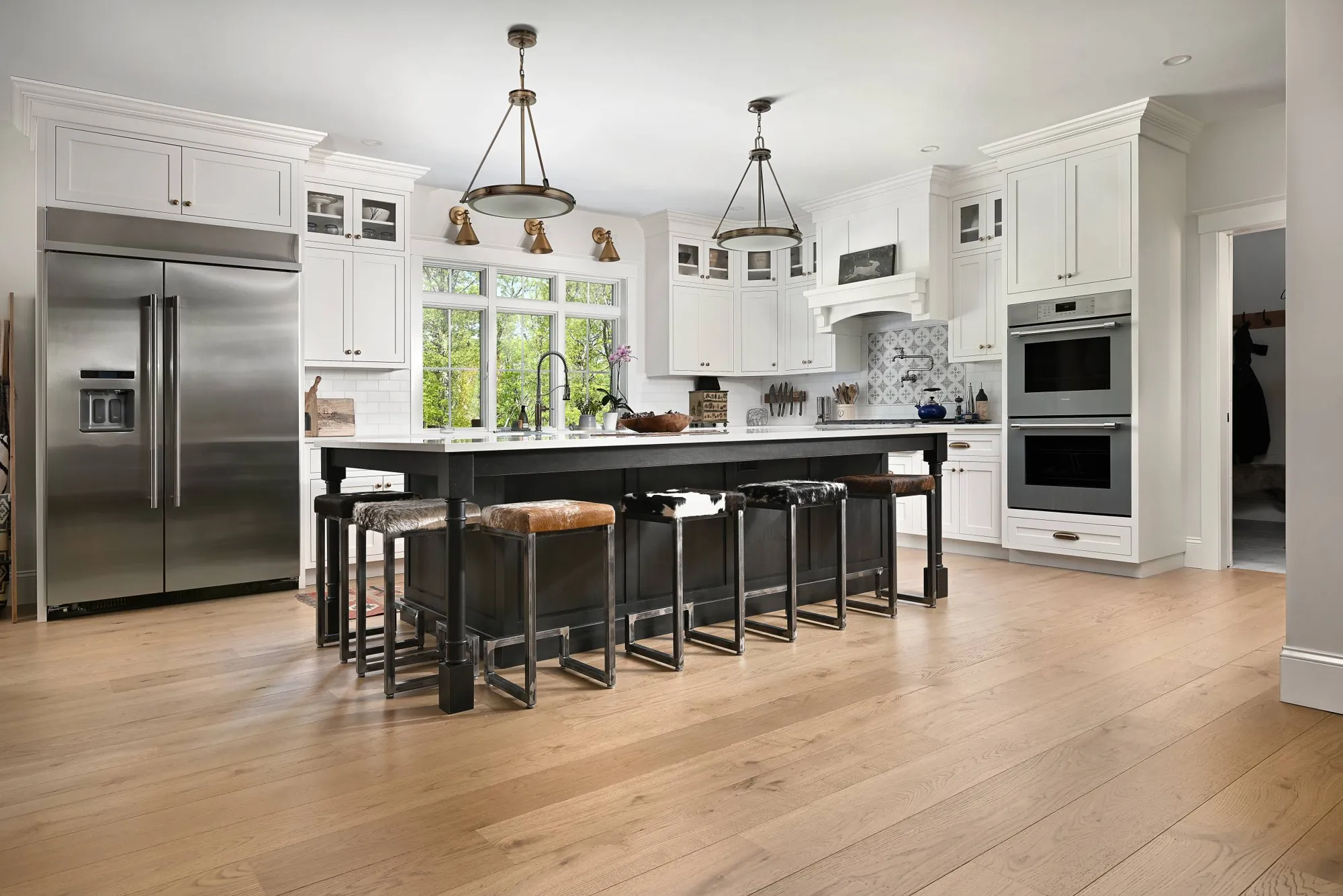 Wide-plank light oak floor in a white kitchen with a long black island